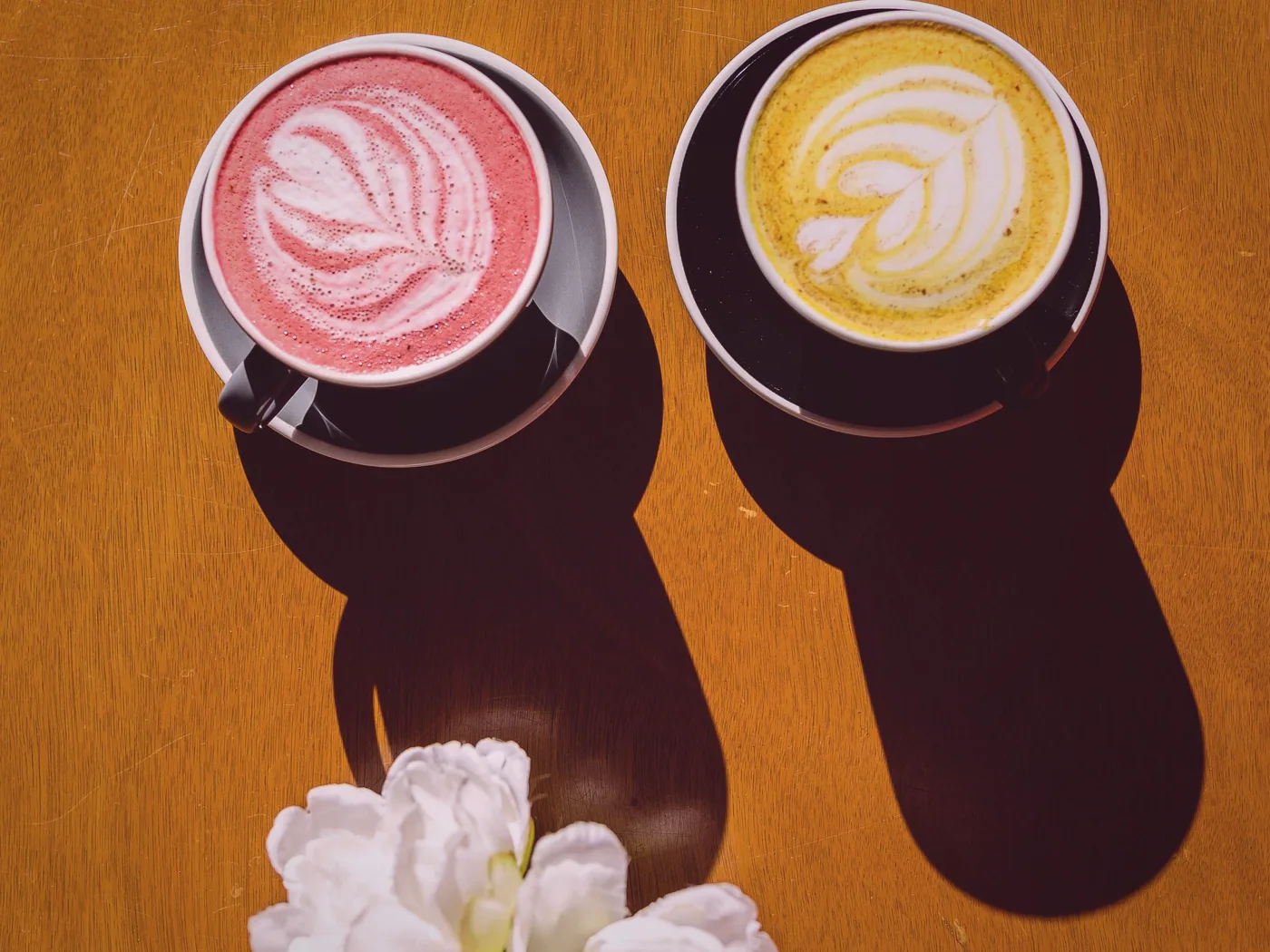 Two coffees on a wooden table, ready to be carried through